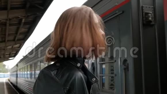 漂亮的红发年轻女子短发戴着眼镜和黑色皮夹克站在美丽的旁边视频的预览图