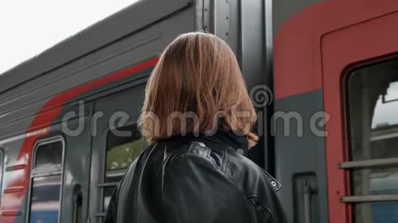 漂亮的红发年轻女子短发戴着眼镜和黑色皮夹克站在美丽的旁边视频的预览图