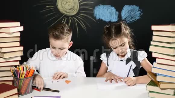 学校观念可爱的孩子们喜欢坐在书桌前桌上放着一大堆书黑板后面放着画视频的预览图