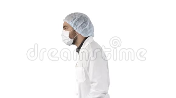英俊的医生穿着制服戴着面具他走在白色的背景上视频的预览图