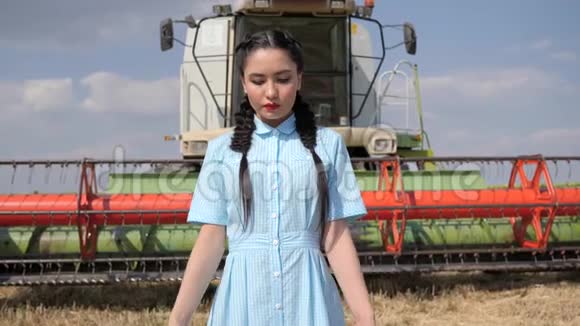 年轻女子在背景农业机械上缓慢地举手视频的预览图