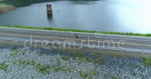 空中一个孤独的美丽女孩正沿着大坝上的道路奔跑视频的预览图
