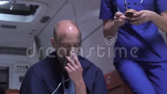 戴氧气面罩的人晚上坐在救护车里视频的预览图