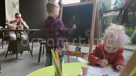 一个男孩和一个女孩在阳台上的桌子上玩视频的预览图