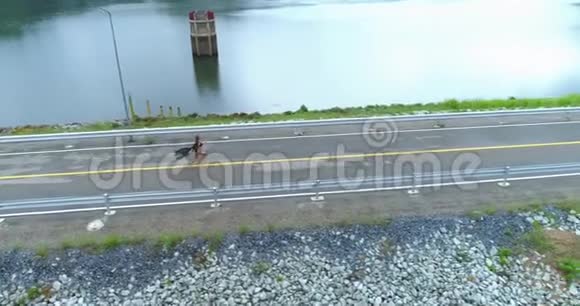 空中一个漂亮的女孩正沿着大坝上的道路奔跑视频的预览图
