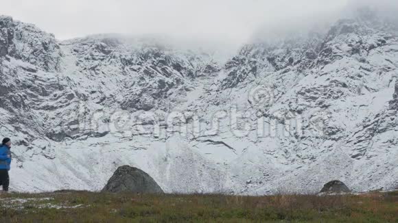 一个背着背包的人独自一人在山里旅行它沿着高高的雪峰视频的预览图