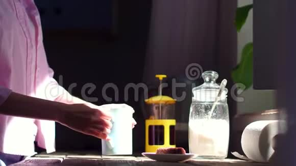 厨房里的年轻女人把糖和茶放进杯子里视频的预览图