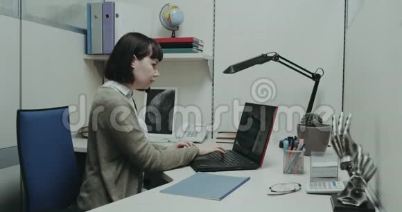 办公室工作人员坐在她的办公桌前看文件并在她的笔记本上核实了一些工作视频的预览图