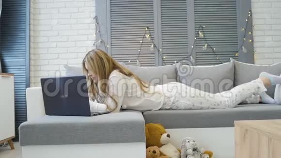 年轻的白种人女孩有智能手机躺在床上上网玩得很开心很放松视频的预览图