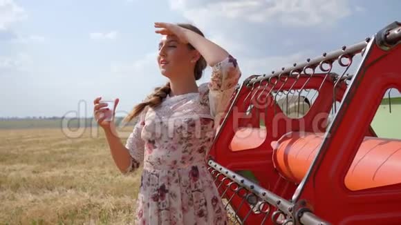 年轻女性在背景红色农业机械上慢动作地喝水视频的预览图