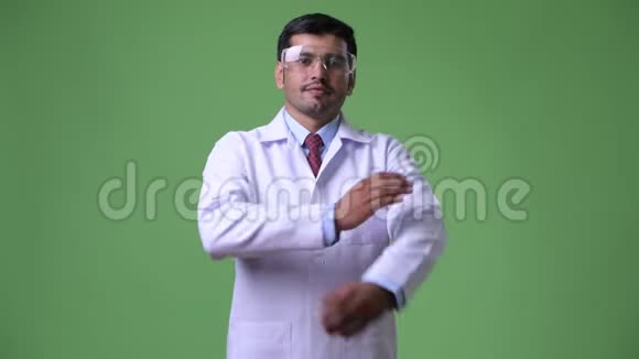 年轻英俊的波斯医生戴着防护眼镜双臂交叉视频的预览图