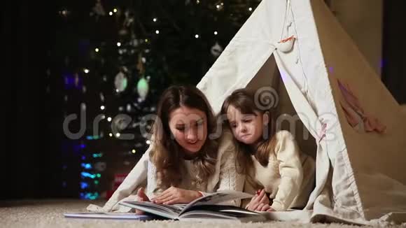 妈妈正在读一个女儿故事因为她和她躺在房子的帐篷里视频的预览图