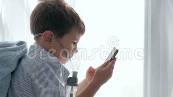 吸入药物男孩戴着面具从吸入器手里拿着手机视频的预览图
