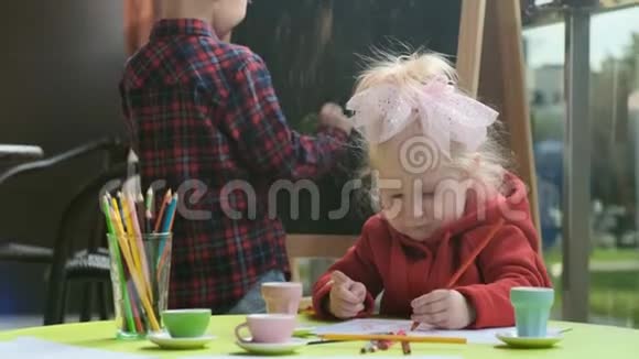 一个男孩和一个女孩在阳台上的桌子上玩视频的预览图