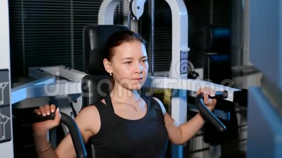 运动按坐在模拟器的肩膀上这个女孩从事健身房4k视频的预览图