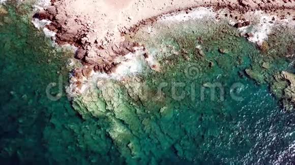 在有着清澈蓝色海岸线的岩石海岸上的水晶般清澈的海浪的鸟瞰图视频的预览图