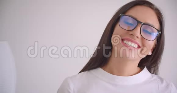 年轻漂亮的白种人女商人戴着眼镜看着镜头高兴地笑着的特写照片视频的预览图
