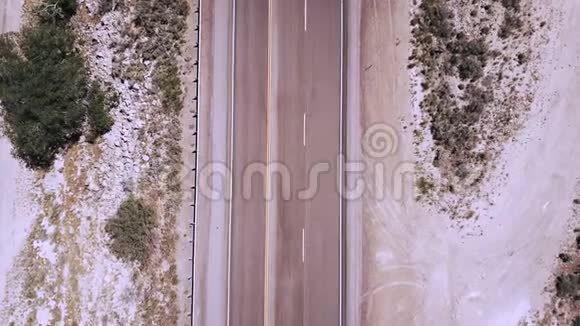 俯视图无人驾驶飞机在沙岩沙漠中部美丽的高速公路上乘坐白色卡车通过摄像头进入视频的预览图