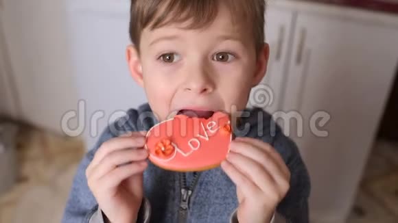 男孩吃着一个心形姜饼上面刻着爱铭文视频的预览图