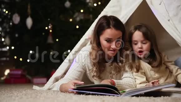 妈妈正在读一个女儿故事因为她和她一起躺在一所房子的帐篷里背景是一个视频的预览图
