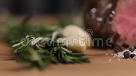 在烤牛肉的背景下加入盐胡椒大蒜和迷迭香的特写颗粒餐厅的食物粮食供应视频的预览图