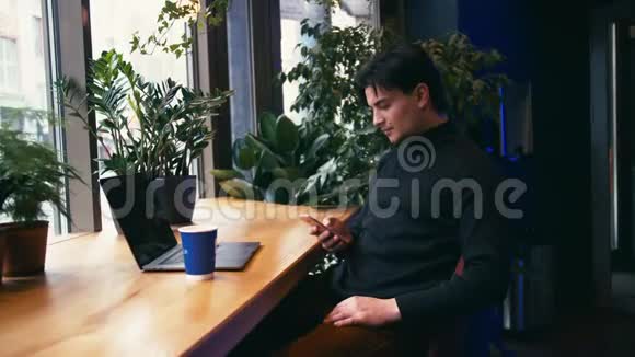 混合种族的人用手提电脑用智能手机在咖啡馆喝拿铁视频的预览图