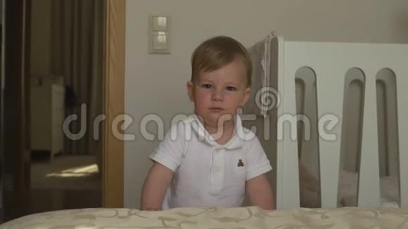 穿着白色的身体马球在公寓里走来走去的小男孩肖像充满好奇和快乐的微笑家庭价值观视频的预览图