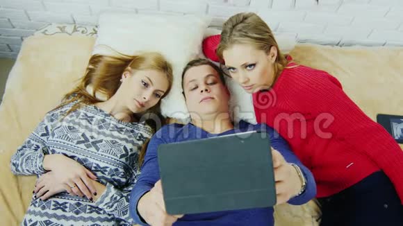 青少年躺在床上在平板电脑上通过Skype进行交流视频的预览图
