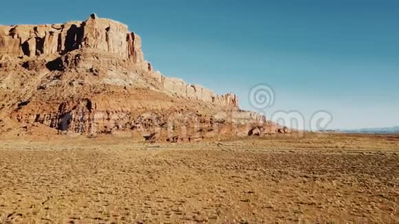 在美国国家公园广阔的干燥荒野景观中无人机飞越砂岩沙漠飞向巨大的岩石山视频的预览图