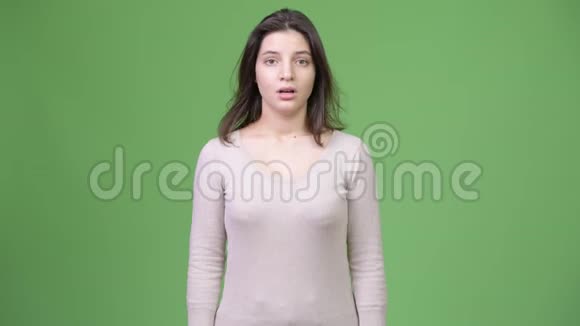 年轻有压力的女人在绿色的背景下耸肩视频的预览图