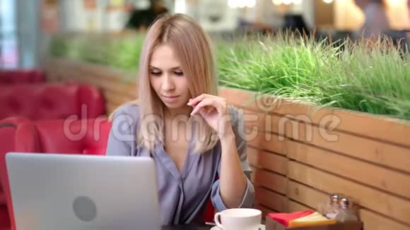 中型照片漂亮的微笑女商人在咖啡馆工作使用笔记本电脑视频的预览图