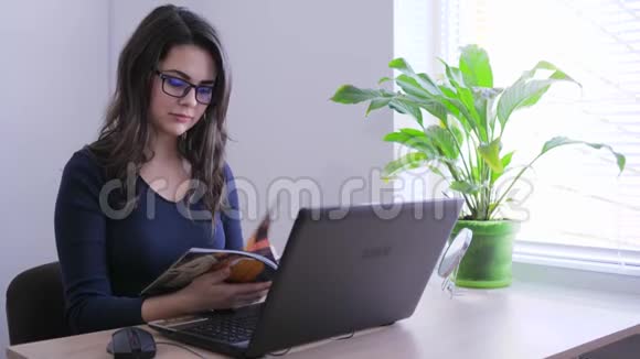 上班时坐在手提电脑前的戴眼镜杂志的女商人视频的预览图