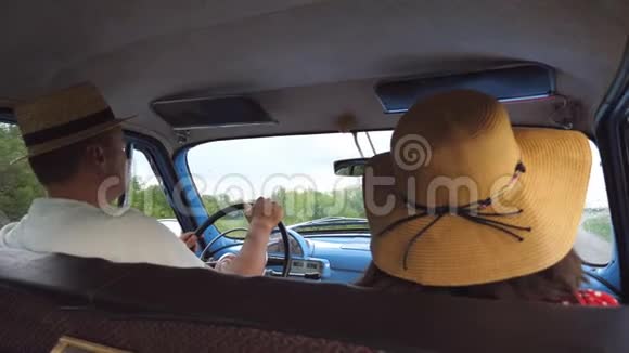 戴着帽子的年轻夫妇开着老式汽车给对方五个快乐的一对骑上旧汽车男子和妇女视频的预览图