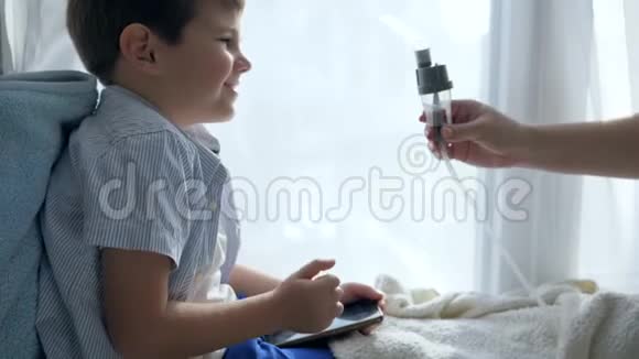 雾化器治疗携带智能手机的患病男孩通过吸入剂呼吸治疗视频的预览图
