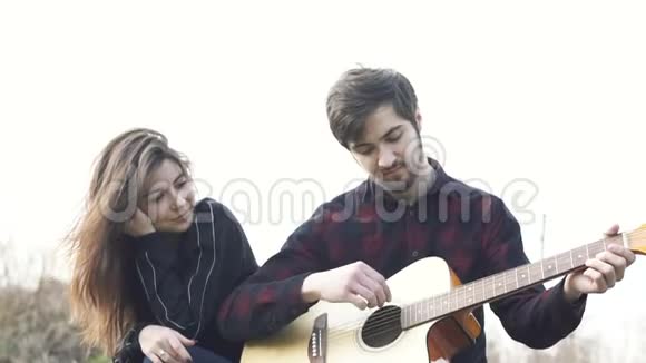浪漫的夫妻坐着男人为女朋友弹吉他户外活动视频的预览图