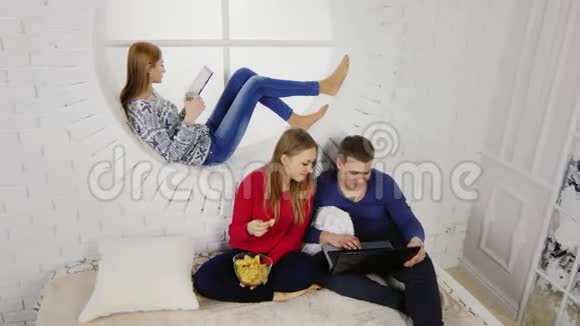 年轻时尚的学生在一起玩平板电脑吃薯片视频的预览图