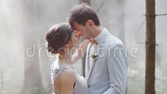 新娘和新郎拥抱彼此站在松林中背景婚礼上有雾视频的预览图