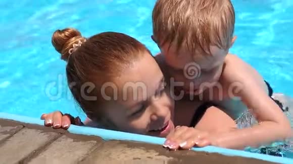 快乐的母亲和她的小儿子在户外游泳池里一起玩视频的预览图