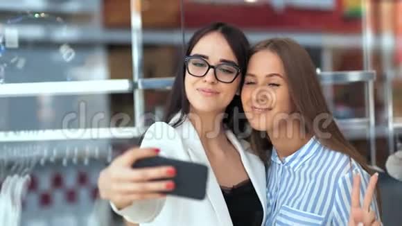 两个美女朋友在现代购物中心购物用智能手机自拍视频的预览图