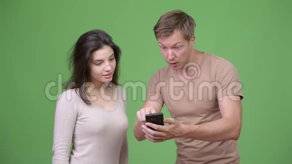 年轻的幸福夫妇用手机看在一起很兴奋视频的预览图