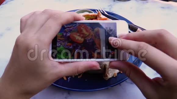 女性手在手机上为社交媒体或博客拍摄素食午餐照片视频的预览图