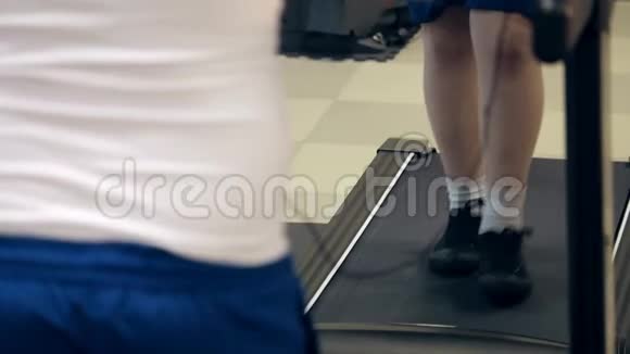 在室内健身运动中穿运动鞋的胖男孩在跑步机上行走视频的预览图