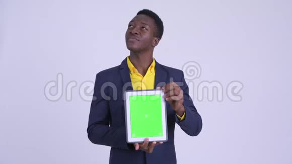 年轻快乐的非洲商人一边思考一边展示数码平板电脑视频的预览图
