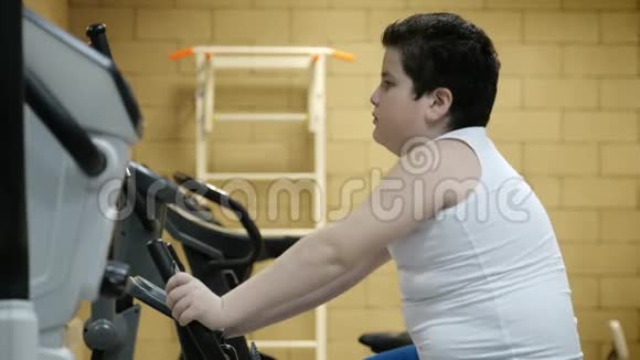肥胖的小男孩在健身房训练固定自行车健康生活方式视频的预览图