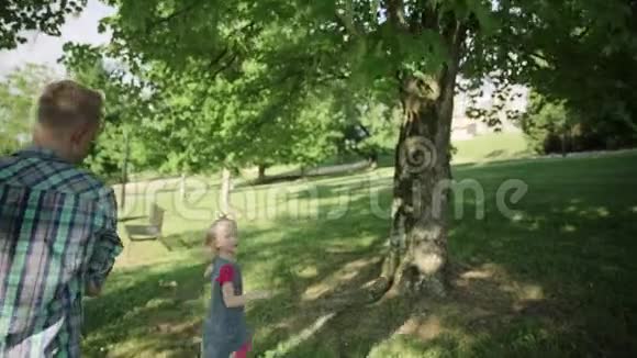 可爱的小男孩女孩和他英俊的年轻爸爸在公园里玩爸爸抱着他的小男孩慢动作全高清视频的预览图