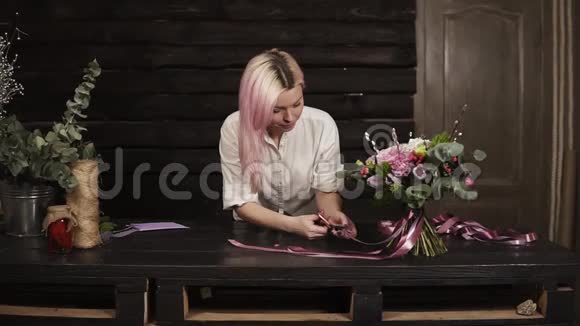 女花匠完成花束的构图用剪刀剪下丝织带的尖端兴奋地视频的预览图