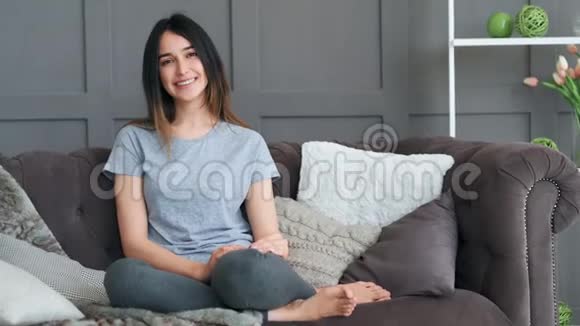 美丽的年轻女子在家里躺在沙发上微笑女孩看镜头的肖像视频的预览图