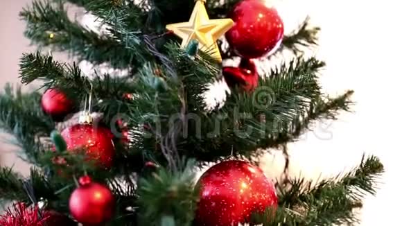 圣诞树上装饰着红色的花苞白色和红色的花环金色的星星和叮当的铃铛视频的预览图