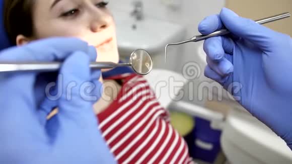 牙医慢慢地把工具带到牙齿上年轻女孩的牙科治疗视频的预览图