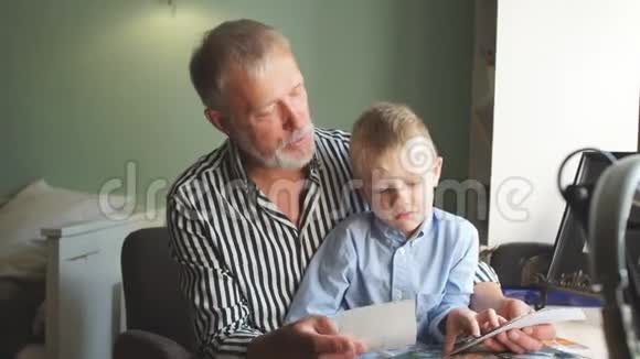 祖父和孙子在家沙发上爷爷和孩子们看老照片视频的预览图